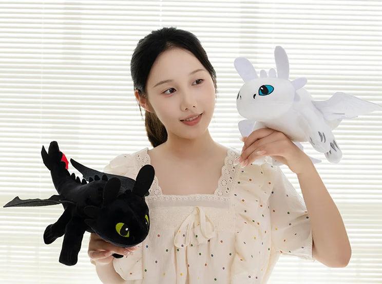 A woman holding Toothless & Light Fury plush toys – Black & White dragon stuffed animals