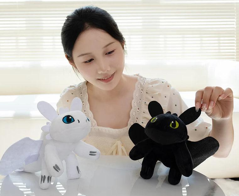 A woman admiring Toothless & Light Fury plushies – Black and White Dragon Stuffed Toys